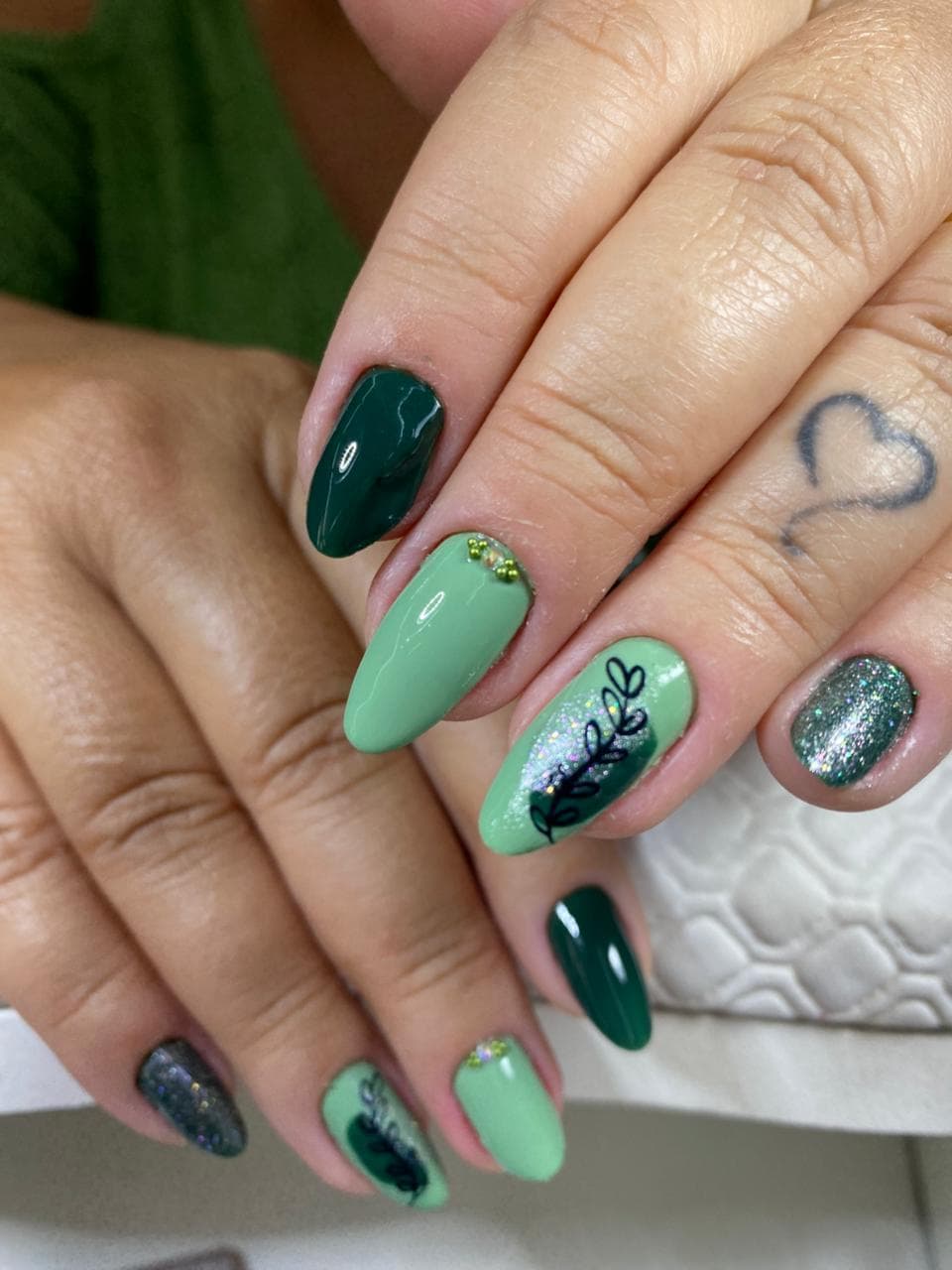 Nail art em tons de verde com detalhes decorativos